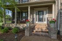 This welcoming brick entry has a beautiful front porch with space for seating as well as a glass front door bringing in loads of natural light!