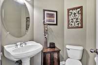 A downstairs powder room with pedestal sink and polished nickel finishes.