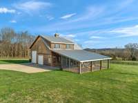 Custom Barn Pro's barn with horse stall and enclosed pen off the stall. Pen has ceiling fans. Barn features RV bay with 14' motorized garage doors and 50 amp plug.