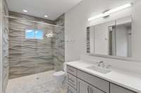 Walk-in curbless shower featured in this ADA accessible bathroom, with radiant heated room / shower floors. Artistic carved limestone tile shower walls.