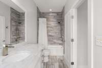 Guest bathroom with modernized tiled tub/shower combo.