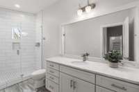 Full guest bath with oversized vanity and quartz countertops.