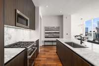 Complete Miele appliances, custom cabinetry, honed marble countertops, and a slab backsplash.