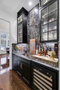 The wet bar has custom glass cabinetry, a Scotsman ice maker, wine cooler and storage. The bar counter and backsplash are granite.