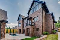 The driveway view shows the side entrance near the kitchen at right. The turf grass section at the bottom is perfect for pets. This view also shows the 2 lower level entrances and the Green Egg grilling balcony just off kitchen.