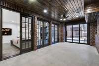 Lower level covered patio/flex area with retractable glass panel door to the pool