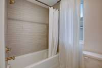 Secondary bath tiled to ceiling with European antique brass fixtures