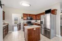 First view of the kitchen, showcasing immaculate tile flooring, stainless steal appliances, and connectivity to the formal dining room in front of home.   Appliances in this main floor kitchen convey with the home.