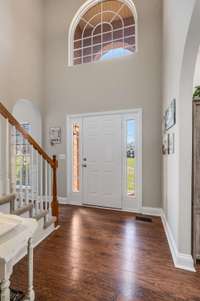 Front entry hall offers side transom windows, window flooring, and direct access to the home's dining room, office (or alternative living space), and stairs to the second level.