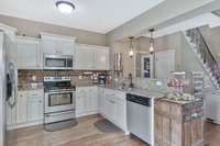 Great kitchen area with white cabinets, granite counters, backsplash and continuation of the hardwood flooring.  All kitchen appliances remain