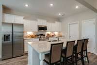 Stock photo showing island and kitchen set up. Your home will have white cabinets and coordinating QUARTZ countertops.