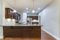 Hardwood floors extend into the kitchen which has a tile backsplash and granite counters.