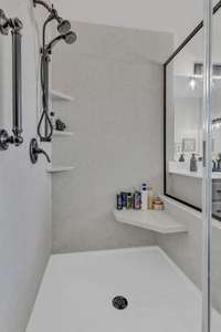 Primary Shower with lots of shelves and sa grab bar.