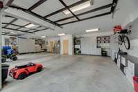 Three car garage with custom storage outlining the perimeter and glass garage doors.