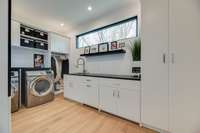 Custom designed laundry room with a sink and an abundance of storage.