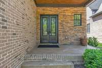 Lovely covered front porch with stained bead board ceiling, stained concrete floor and gorgeous front entry doors.