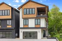 Three level home, partial brick with siding and cedar accents, with a custom glass paneled oversized two-car garage.