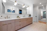 Your primary bath features a steam shower, custom white oak cabinetry with mitered edged quartz countertops, along with a custom mirror.