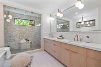 Steam Shower with dual shower heads, custom white oak cabinetry, mitered quartz counter tops, and a soaking tub.