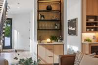 Wet bar, with a sink, pull-out trash can, and a paneled icemaker, along with custom built floating metal shelves