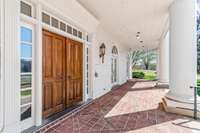 Double front doors, spacious brick covered porch with stately columns.