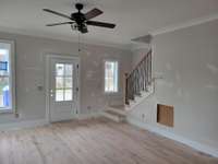 Living space. One of many ceiling fans. Hardwood steps lead to second floor.