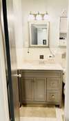 Lovely updated bathroom with tile flooring, upscale vanity and mirror. New lighting, tile bathtub/shower combination with tile surround.