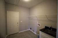 Laundry room has tile floors and sink with storage space!