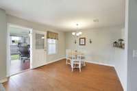 Dining area with hard woods, leading to sunroom.