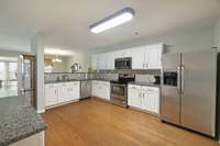 Open kitchen with stainless appliances and granite countertops.