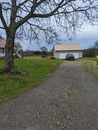 Detached 2 car garage with concrete slab, power, and fully finished wood walls.