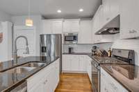 The kitchen offers stainless steel appliances including a new microwave and gas range.