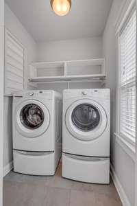 The laundry room offers natural light with a sunny window. Washer and dryer remain.