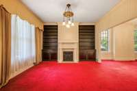 Formal living and dining rooms with original unfinished hardwood flooring under the wall-to-wall carpet and pad.  There is an actual window to the right of the fireplace behind the wooden bookcase on that side of the fireplace.