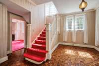 Large entry foyer with solid wood and beveled glass front door with hand laid Teak wood flooring and antique glass light fixture.