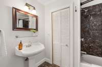 Primary bathroom with tub-shower and linen closet.
