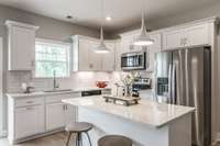 The kitchen is bright white with lots of cabinet storage and counter top space.