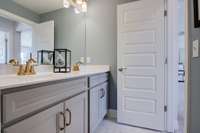 Guest bathroom upstairs features dual vanities & tiled floor.