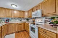 Nice clean kitchen with wood cabinets and stove, built in microwave, dishwasher, and refrigerator to stay.