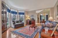 The formal living room is splashed with light from the big bay window