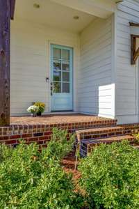 A charming Robin's Egg blue front door invites you inside this light filled lovely home! Porch details such as the herringbone patterned masonry work and a handsome wood column add to the entryway.