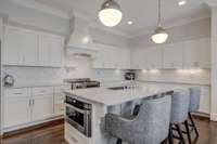 A white arabesque marble backsplash frames the classic gourmet kitchen perfectly! The handcrafted hood is one of many lovely features within the kitchen area.