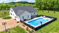 Back view of white painted brick home with pool