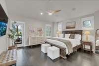 The primary bedroom with vaulted ceiling features a door onto the covered deck and plantation shutters