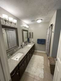 DOUBLE VANITIES FEATURING GRANITE COUNTERTOPS IN PRIMARY BATHROOM.