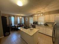 UPDATED CABINETS, GRANITE COUNTERTOPS, CONVENIENT ISLAND, & TILE FLOORS ARE ALL PART OF THIS SPACIOUS KITCHEN.