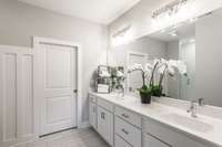 Moving into the primary bathroom and it has a spa like feel with bright white cabinets and tile.