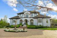 The circular brick driveway creates a grand sense of arrival along with the fountain