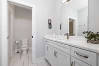 Modern lighting, tile flooring and beautiful cabinetry in this guest bathroom.