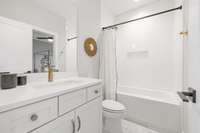 This upstairs guest bathroom includes a shower/tub combination with tile surround and a niche for bath products.